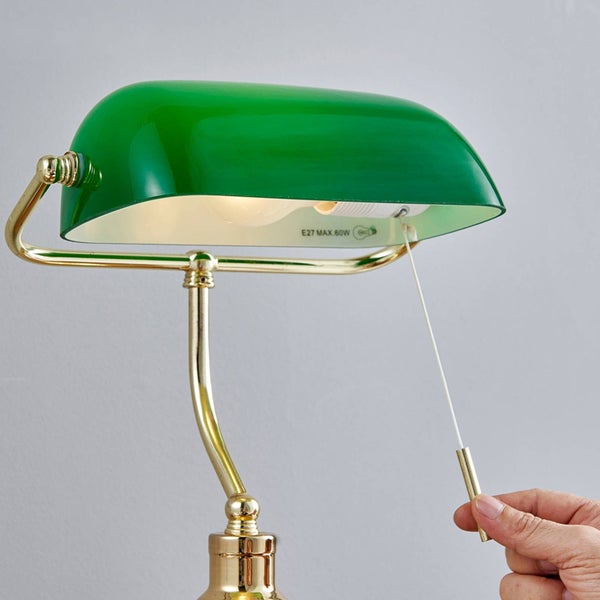 Grüne Schreibtischlampe aus Metall mit Zugschalter wird von einer Hand bedient.
