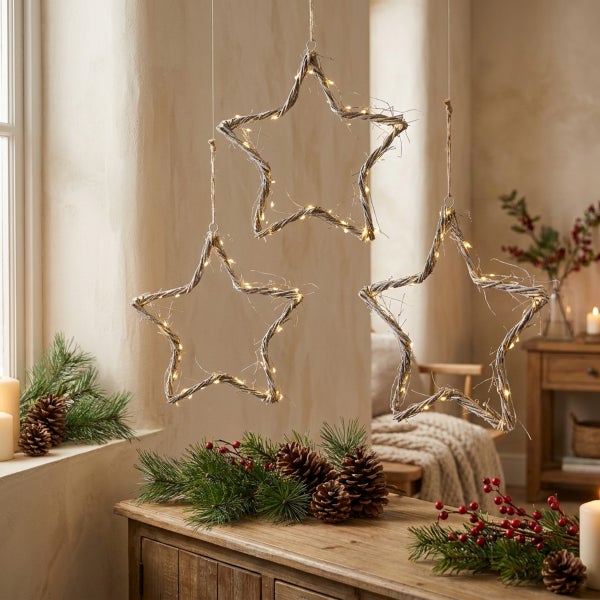Drei hängende LED Weihnachtssterne aus Naturzweigen mit Lichterkette als weihnachtliche Fensterdekoration im Wohnzimmer.