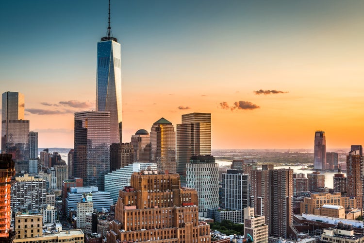Panoramablick auf die Skyline von New York City bei Sonnenuntergang mit dem One World Trade Center im Vordergrund.