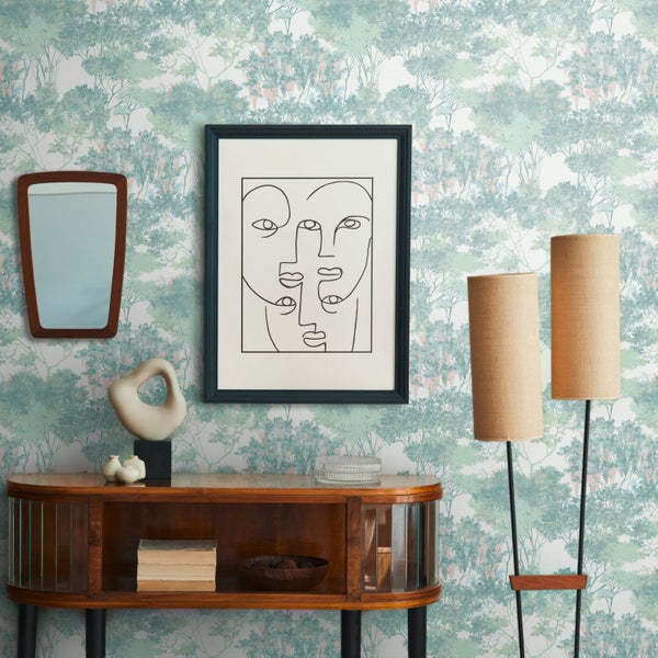 Dekorative Vasen unterschiedlicher Formen und Materialien vor einer Tapete mit Baumdesign.