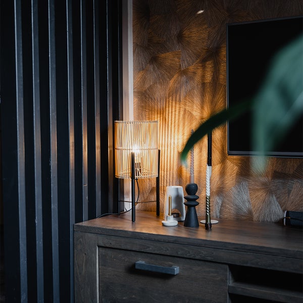 Dekoratives Wohnzimmer mit Lampe, Kerzen und Fernseher auf einem dunklen Holzschrank