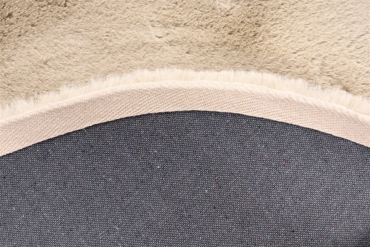 Detailansicht eines Kunstfellteppichs mit weichem Flor, gewebter Einfassung und strukturierter Rückseite.