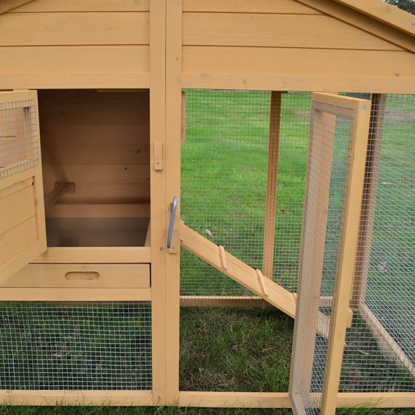 Kleintierstall aus Holz mit integriertem Auslauf, Rampe und ausziehbarer Schublade auf einer Rasenfläche.