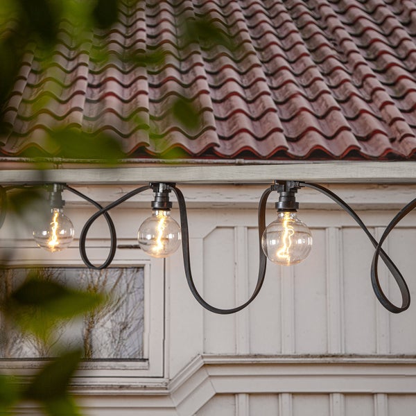 Lichterkette mit Glühbirnen unter einem Dachvorsprung.