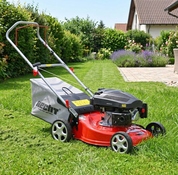 Hecht Benzin-Rasenmäher in einem hellen, gepflegten Garten auf einer Rasenfläche mit Haus im Hintergrund.