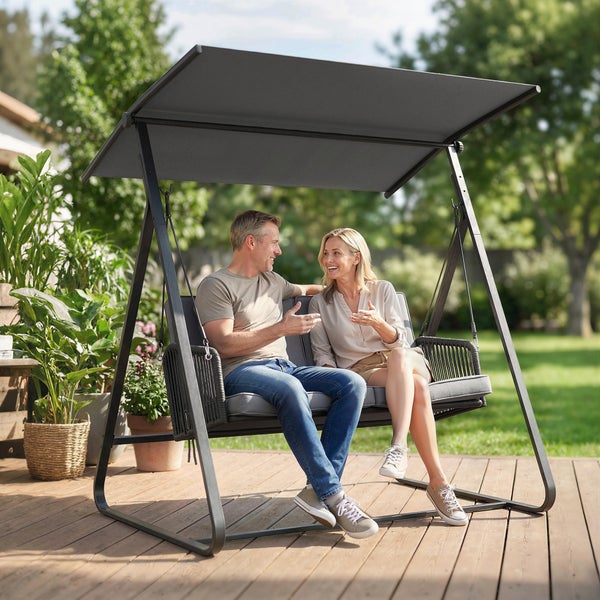 Hollywoodschaukel mit verstellbarem Sonnendach auf einer Holzterrasse, 2-Sitzer mit grauen Polstern und modernen Seil-Armlehnen.