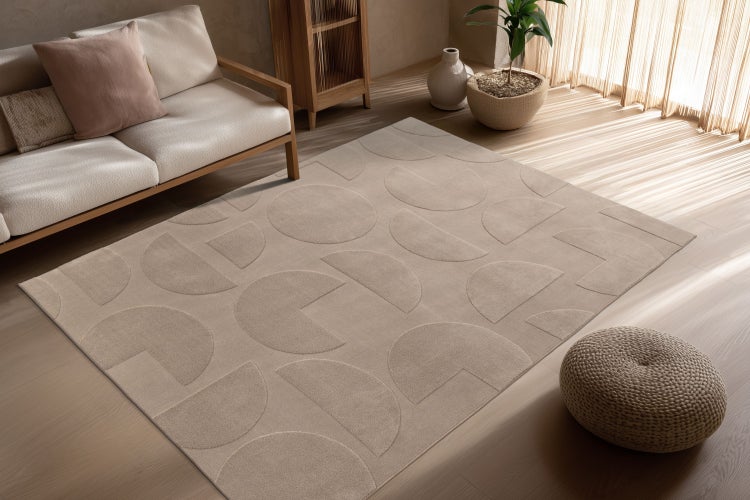 Wohnzimmer mit rechteckigem Teppich mit geometrischem Halbkreis Muster auf Holzboden vor Sofa mit Holzelementen und Zimmerpflanze