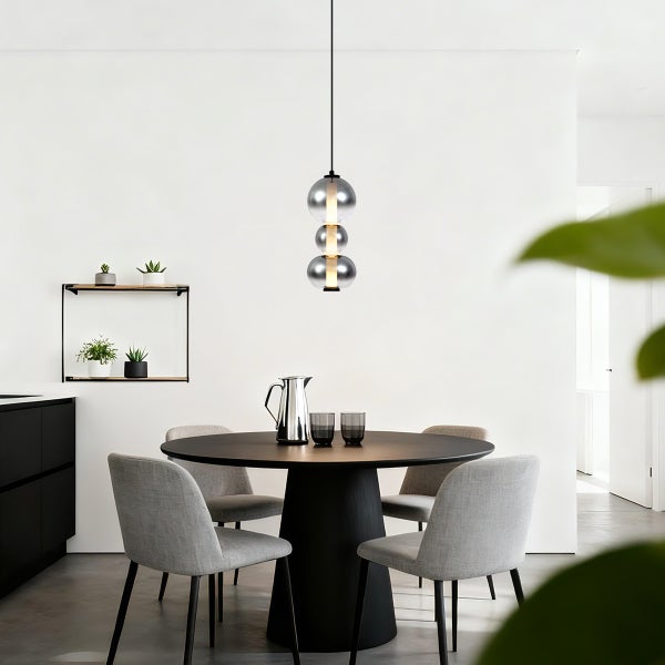 Esszimmer mit rundem Tisch, Stühlen und Hängelampe mit drei Glaskugeln