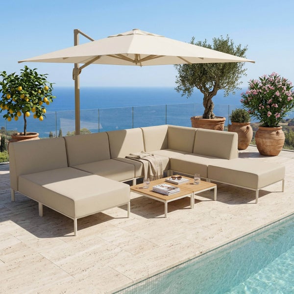 Helle Lounge-Sitzgruppe auf einer Terrasse am Pool mit großem Ampelschirm, Holztischen und Pflanzen vor Meerblick.