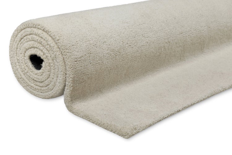 Aufgerollter Teppichboden in Beige mit weichem Flor.