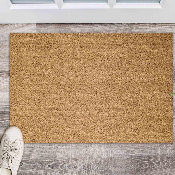 Fußmatte aus Kokosfasern vor einer Tür auf einem Holzboden