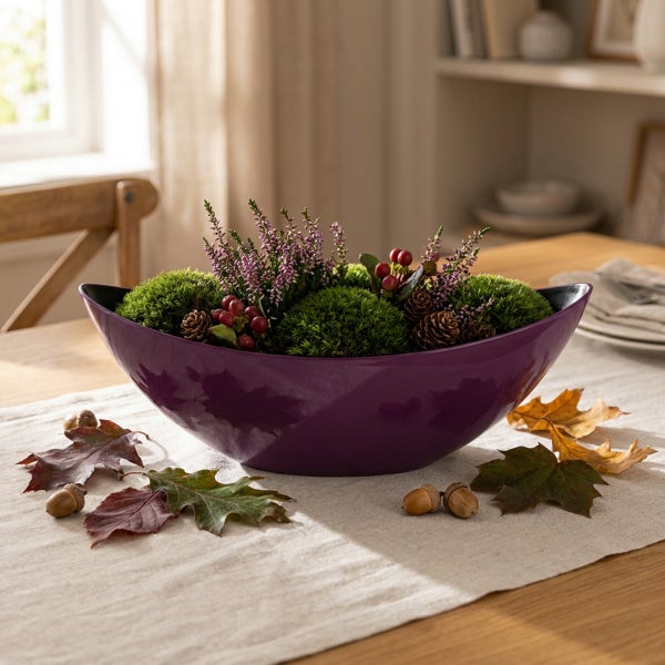 Dekorative Schale mit herbstlicher Bepflanzung aus Heidekraut Moos Zapfen und Beeren auf einem Holztisch mit Herbstblättern dekoriert