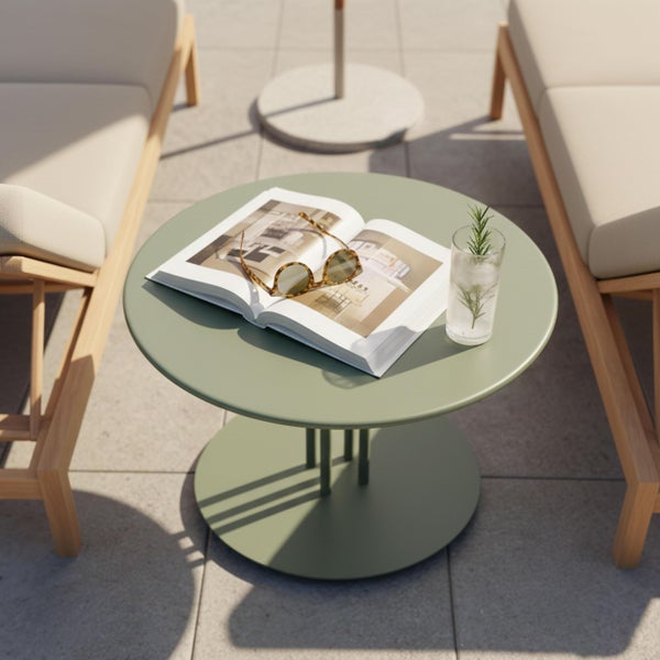 Runder Metall-Beistelltisch auf einer sonnigen Terrasse zwischen zwei Holz-Sonnenliegen mit einem Buch und einem Glas.