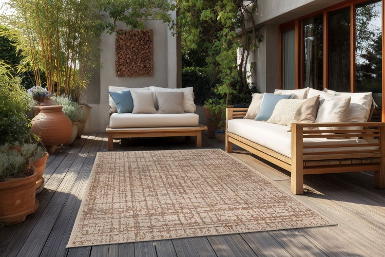 Outdoor-Teppich mit geometrischem Muster auf einer Terrasse mit Holzmöbeln und Pflanzen in Terrakottatöpfen.