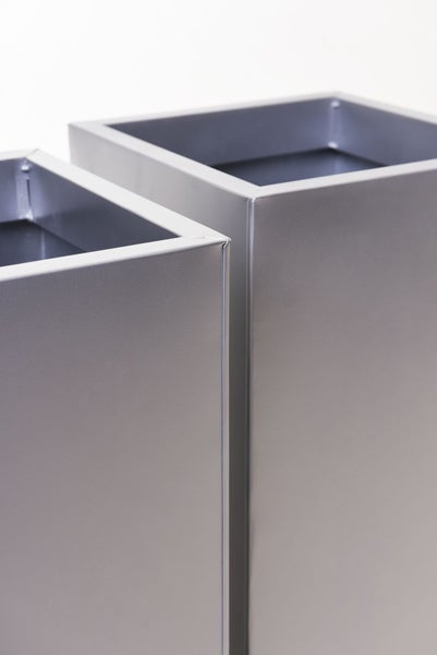 Nahaufnahme von zwei hohen quadratischen Pflanzkübeln aus Metall mit matter Oberfläche.
