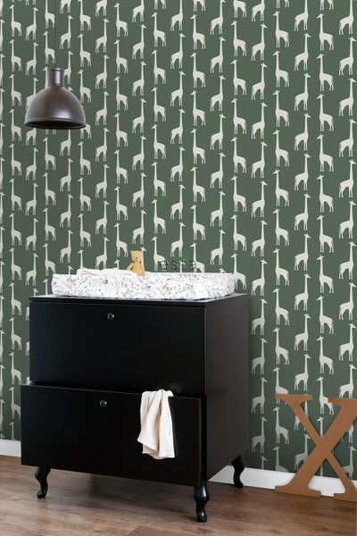 Kinderzimmer mit Wickelkommode vor Tapete mit Giraffenmuster.