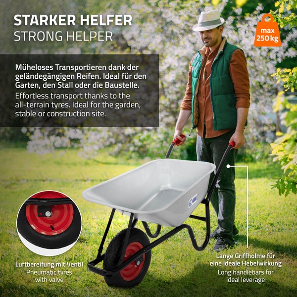 Ein Mann im Garten nutzt eine Schubkarre mit langen Griffholmen, grauer Wanne und Luftbereifung. Maximale Tragkraft 250 Kilogramm.