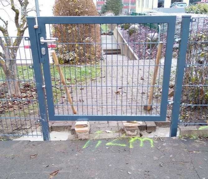 Anthrazitfarbenes Gartentor aus Metall mit Doppelstabmatten und Drückergarnitur, eingebaut in einen Zaun im hellen Außenbereich.