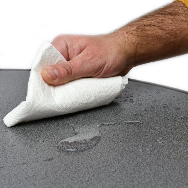 Eine Hand wischt mit einem Papiertuch eine Oberfläche ab.