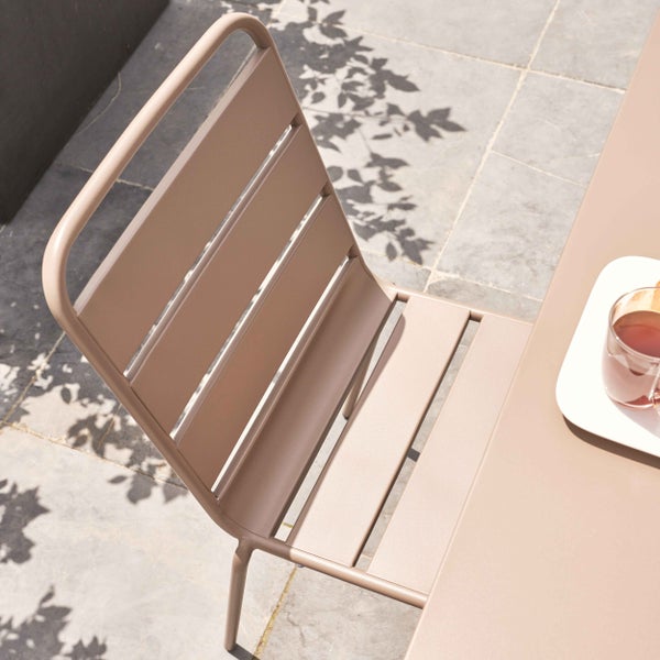 Moderner Gartenstuhl aus Metall mit Latten-Design auf einer hellen Terrasse neben einem Tisch.