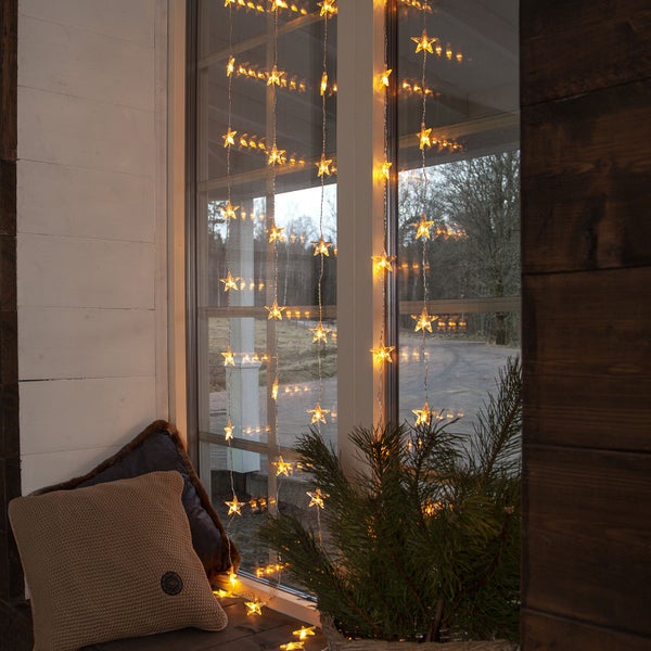 Fensterdekoration mit Sternenlichterkette und Kissen
