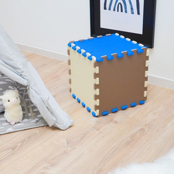 Puzzlematte aus Schaumstoff als Würfel zusammengesetzt in einem hellen Kinderzimmer neben einem Spielzelt und einem Stofftier.