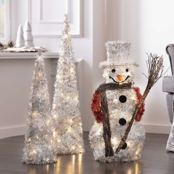 Dekorative Schneemannfigur und zwei Kegel, beleuchtet für eine festliche Atmosphäre.