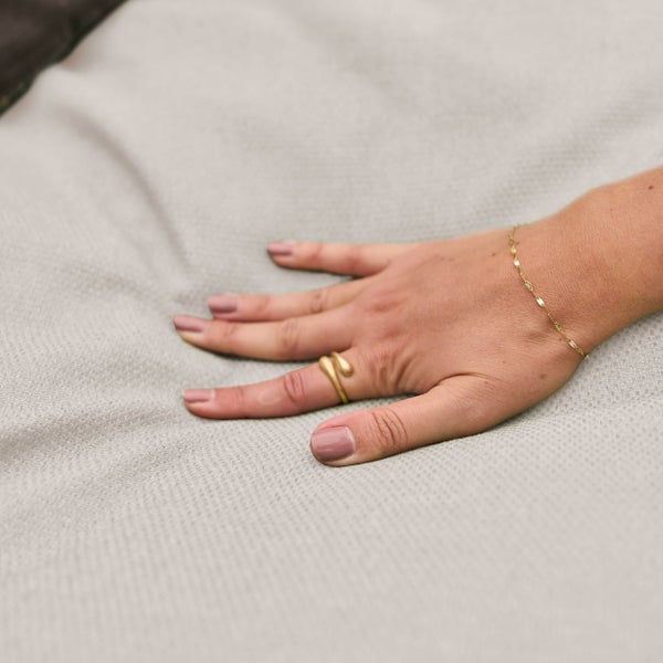 Hand auf einem weichen, fein gewebten Stoff.