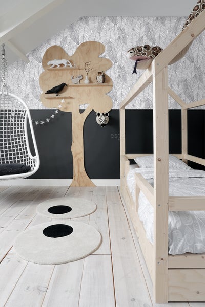 Helles Kinderzimmer mit Holzbett, Schaukelstuhl, Baumregal und runden Teppichen