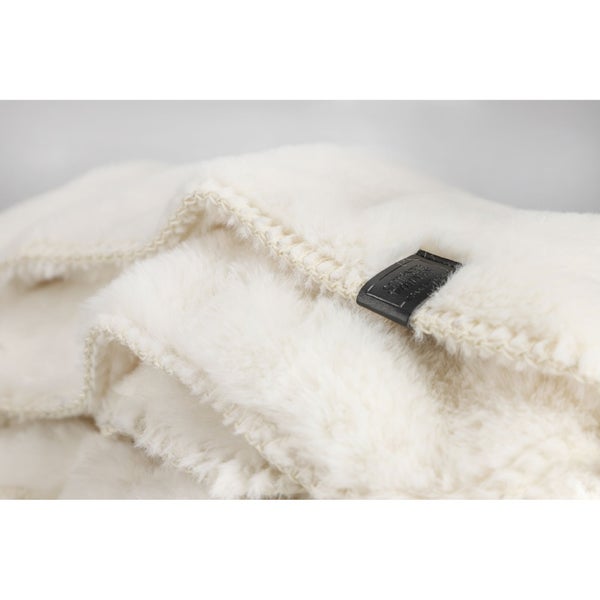 Nahaufnahme einer weißen Kuscheldecke mit einem Lederetikett