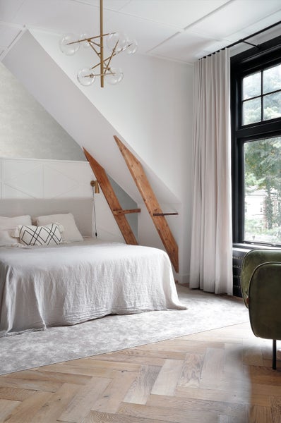 Schlafzimmer mit Bett, Deckenleuchte, Fenster und Holzbalken