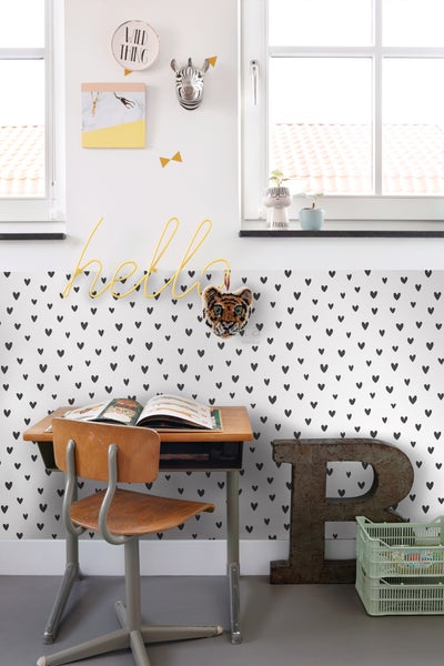Kinderschreibtisch mit Stuhl in einem Zimmer mit herzförmiger Tapete.