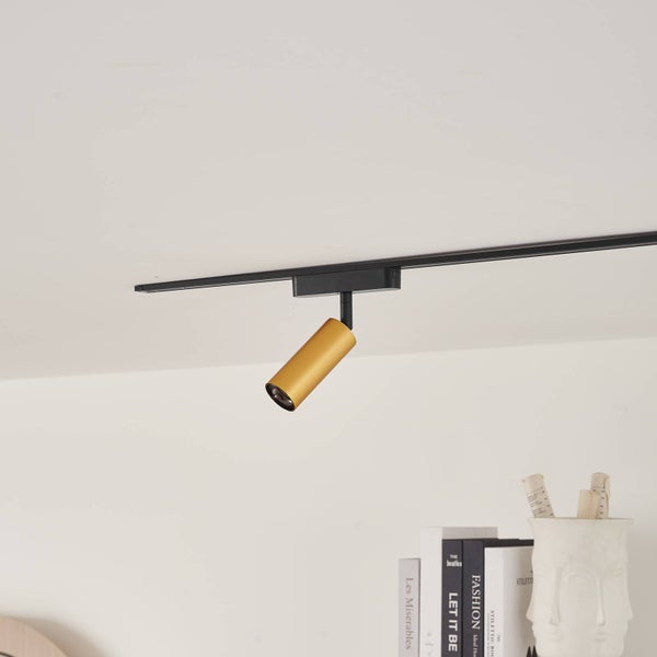 Zylindrischer Schienenstrahler in Gold, montiert an einer schwarzen Stromschiene.