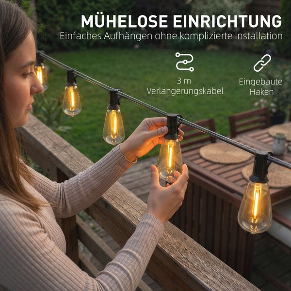 Eine Frau bringt eine LED-Lichterkette mit Edison-Glühbirnen an einem Holzbalkongeländer an. Mit 3 Meter Verlängerungskabel und integrierten Haken.