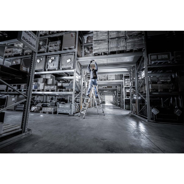 Eine Person steht auf einer Stufenleiter in einem Lagerhaus.