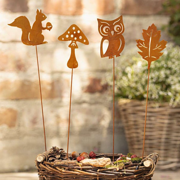 Dekorative Gartenstecker mit Tiermotiven und Pilzen in einem Korb.