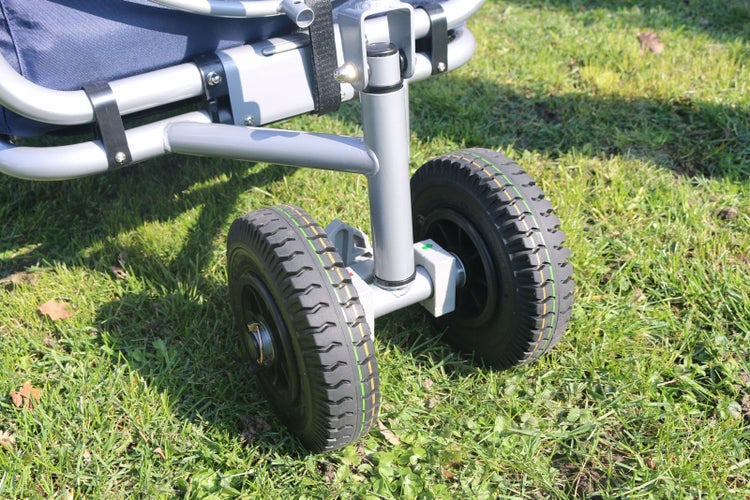 Detailansicht der Räder eines Bollerwagens mit profilierten Gummireifen auf einer Wiese.
