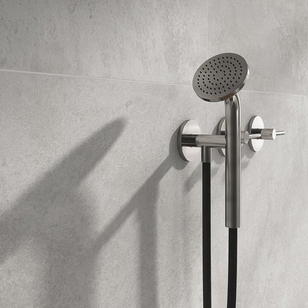 Moderne Wandarmatur mit Handbrause und Brauseschlauch an einer gefliesten Wand montiert