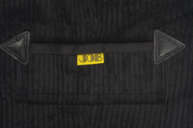 Detailansicht einer Tasche aus Cord mit Lederverstärkungen und JCB Logo.