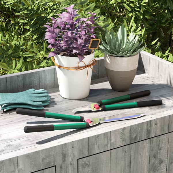 Szene mit Gartengeräten, Pflanzgefäßen und Gartenhandschuhen auf einem Gartentisch