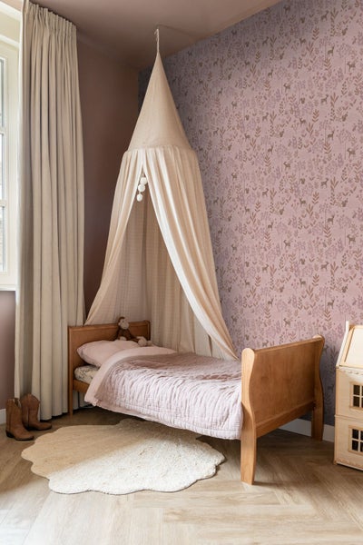 Kinderzimmer mit Bett unter Baldachin, gemusterten Tapeten und Spielhaus