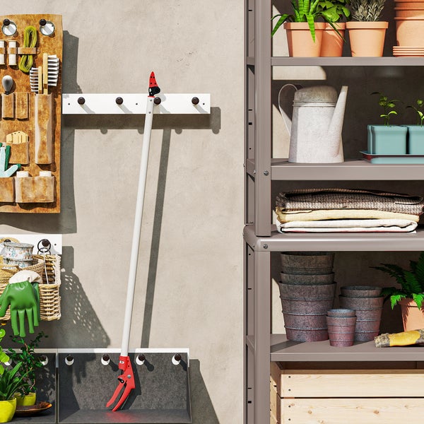 Gartenwerkzeuge und Pflanzen auf Regalen und an Haken an der Wand
