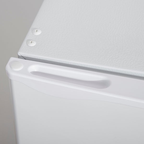 Nahaufnahme eines weißen Kühlschranks mit Griffmulde an der Tür und Abdeckkappen für Schrauben auf der Oberseite.