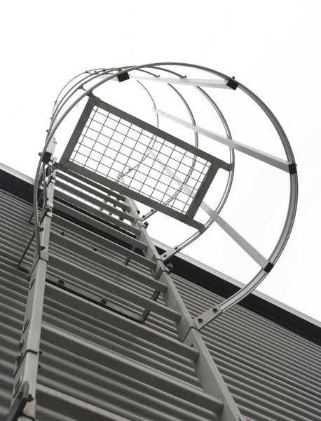 Industrielle Leiter mit Käfigschutz an einer Gebäudefassade