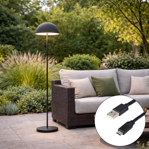 Moderne Außenstehleuchte mit USB-Ladekabel neben einem Gartensofa im Außenbereich.