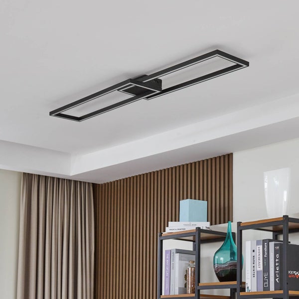 Moderne schwarze LED-Deckenleuchte mit zwei rechteckigen Rahmen an einer weißen Decke in einem Raum mit Holzpaneelen und einem Regal.
