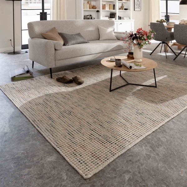 Gewebter Teppich mit Punktmuster im hellen, modernen Wohnzimmer mit Sofa und rundem Couchtisch aus Holz.