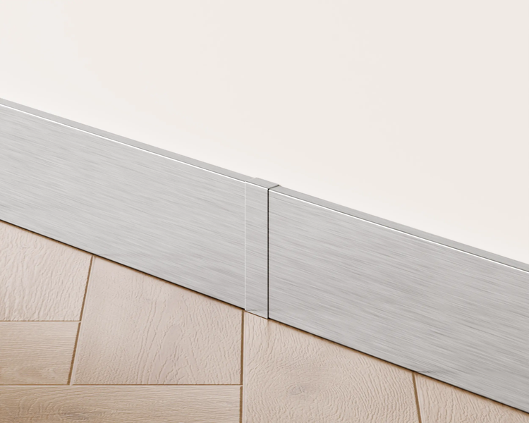Sockelleiste aus Metall vor einer Wand und einem Holzboden