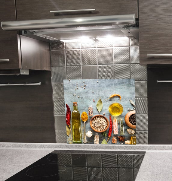 Küchenszene mit Herdabdeckplatte und Spritzschutz mit Gewürzmotiv