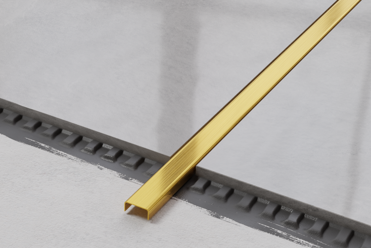 Goldfarbenes Fliesenzierprofil auf grauem Untergrund